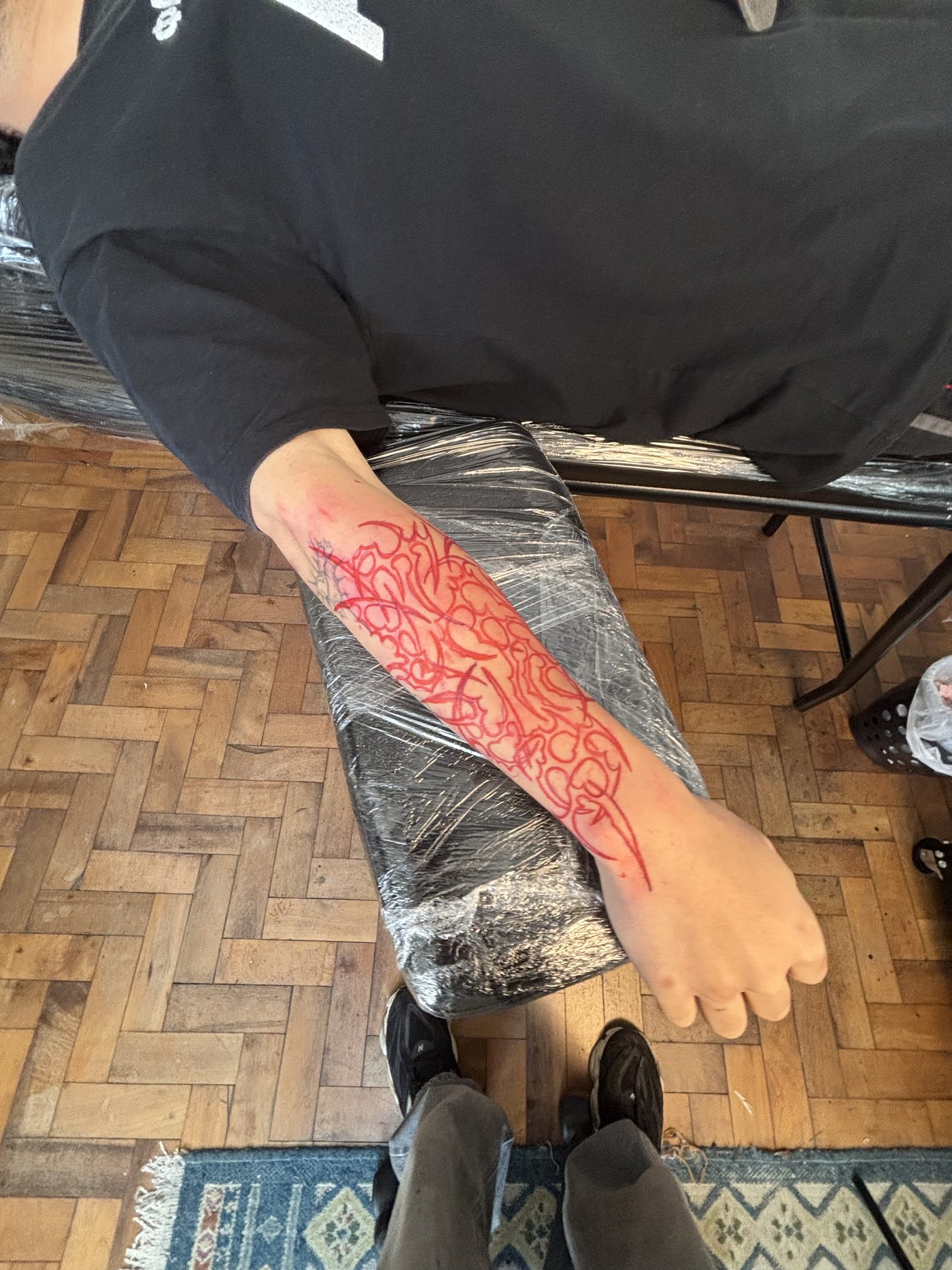 Antebraço recém tatuado com chamas em vermelho