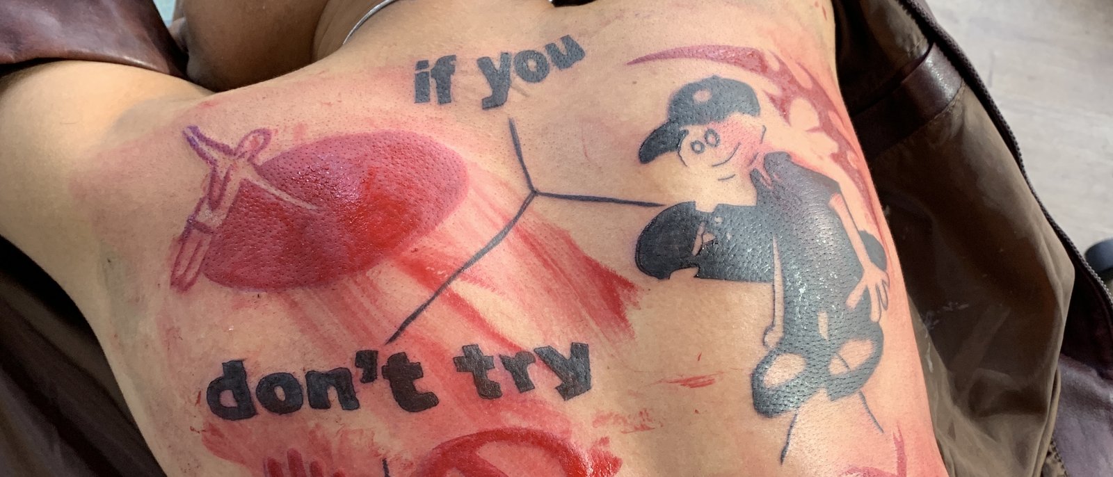 Costas fechadas, peça recém tatuada em preto e vermelho